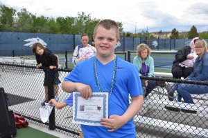 Caleb is getting certificate of congratulations for graduating Tennis Buddies of Reno.